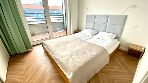 - une chambre avec un lit et une grande fenêtre dans l'établissement ApartamentLesznoPL Family Friendly, à Leszno