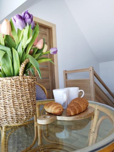 a glass table with croissants and a basket of flowers at Jagodowe Domki in Ciche