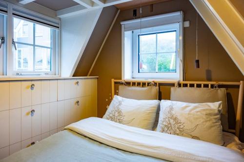 a bedroom with a bed and two windows at Fisherman's Cottage - Surf Retreat in Wijk aan Zee