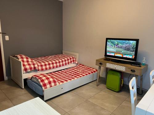 マル・デル・プラタにあるHermoso departamento a la calle a 300 mts del marのベッド、デスク、テレビが備わる客室です。