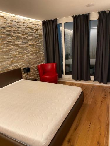 1 dormitorio con 1 cama y 1 silla roja en APPARTAMENTO SILVIA en Bressanone
