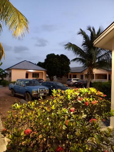 a blue truck parked in a parking lot with flowers at Lord's Hands Guesthouse Hotel in Winneba