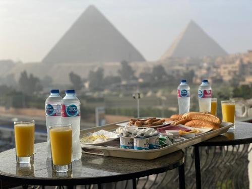 stół z tacą z jedzeniem i butelkami soku pomarańczowego w obiekcie Unique Pyramids View INN w Kairze