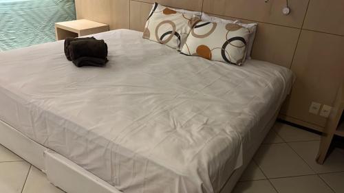 Una cama blanca con dos bolsas encima. en Flat Barra da tijuca, en Río de Janeiro