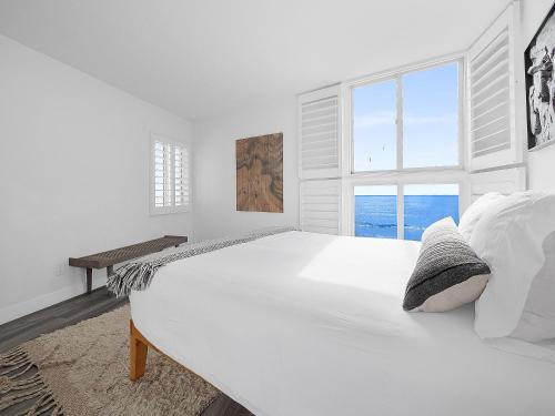 a white bedroom with a large bed with a window at Sunset Cliffs Lookout - Ocean Front Luxury Condo in San Diego