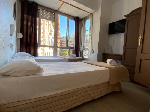 um quarto com 2 camas e uma grande janela em LÀtic Rooms em Alicante