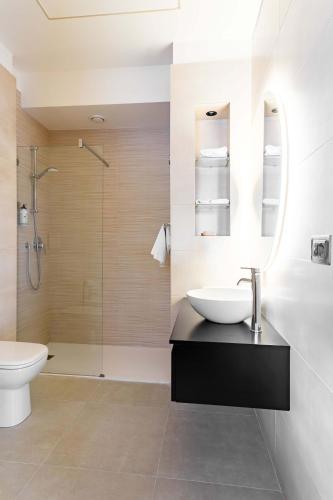 a bathroom with a sink and a toilet and a shower at La Pergola Suites in Dossobuono
