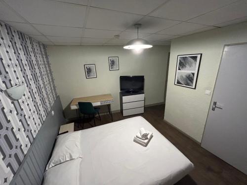 een kamer met een bed, een bureau en een televisie bij Hôtel Broisin in Aix-les-Bains