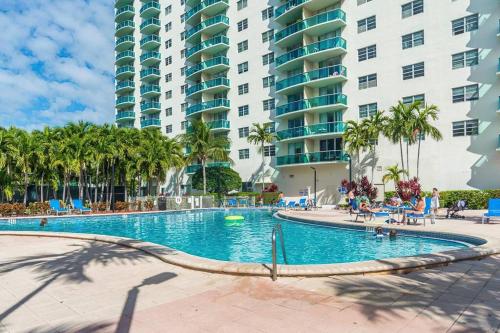 una piscina en un complejo con palmeras y edificios en Sunny Isles Apartment en Sunny Isles Beach