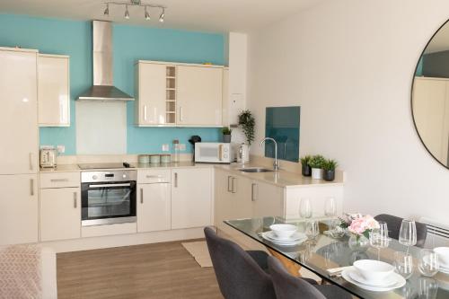 a kitchen with white cabinets and a table with chairs at Modern, comfy 2 bedroom flat in Hatfield town centre in Hatfield