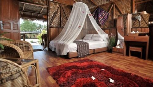 a bedroom with a bed with a hammock in it at Bintan Brzee Beach in Bintan Island - Bungalow 1 in Berakit