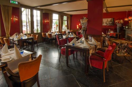 un restaurante con mesas, sillas y paredes rojas en Die Port van Cleve en Enkhuizen