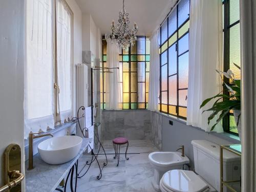 un bagno con due lavandini, due servizi igienici e un lampadario a braccio di L'Angolo di Casa Verrua a Torino