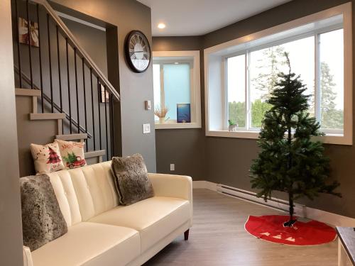 a living room with a white couch and a christmas tree at Licensed Mountain Retreat Garden House Near Heritage Park, Cultus Lake in Chilliwack