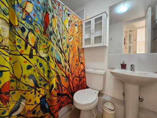a bathroom with a toilet and a colorful shower curtain at Oceana Suites Marina Del Sol in La Serena