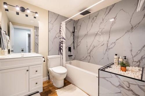 a bathroom with a toilet and a tub and a sink at New&Stylish&Cozy Suit near Spruce Meadows Sleeps 6- Backyard-EV in Calgary