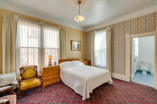 a bedroom with a bed and a chair and windows at Lodi Hill House in Lodi
