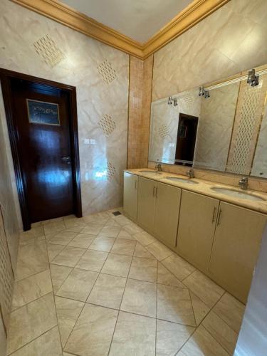 a bathroom with two sinks and a wooden door at فيلا للإيجار اليومي جدة jar villa in Al Kura