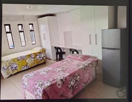a room with a bed and a table and a refrigerator at GLOBAL PRIDE in Soweto