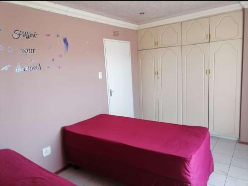 a bedroom with a pink bed and white cabinets at GLOBAL PRIDE in Soweto