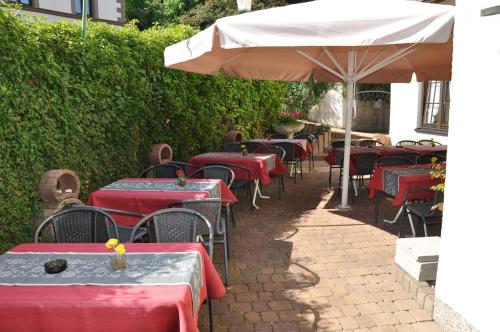 a row of tables with red tables and an umbrella at Hotel Restaurant Zum Schwan in Mettlach