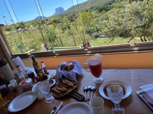 einen Tisch mit Speisen und Getränken und ein Fenster mit Aussicht in der Unterkunft Chalé Capão Vibes in Vale do Capao