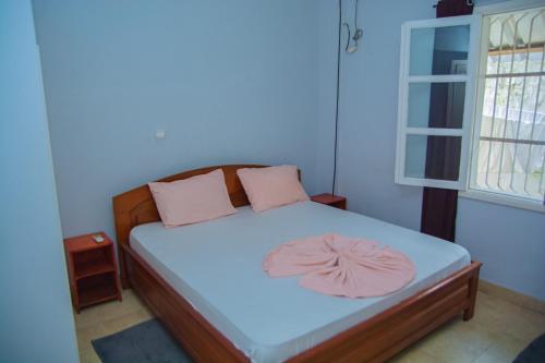 - une petite chambre avec un lit et des oreillers roses dans l'établissement studio brasserie, à Pointe-Noire