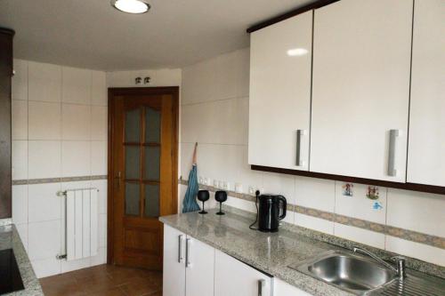 uma cozinha com armários brancos e um lavatório em AL 2 hab BR 2 baños 6 pax em Madri