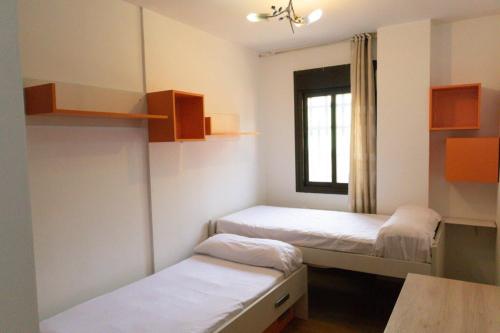 um pequeno quarto com 2 camas e uma janela em AL 2 hab BR 2 baños 6 pax em Madri