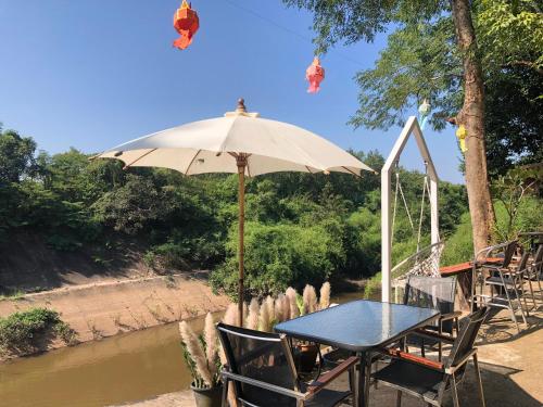 a table and chairs under an umbrella next to a river at ที่พักฮิมฝายบึงกาฬ 