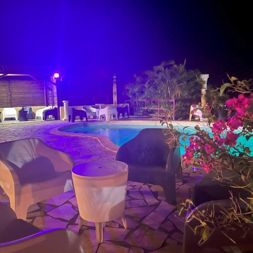 a swimming pool at night with chairs and tables at SAPHIR-Villa Le Colibri in Dubédou