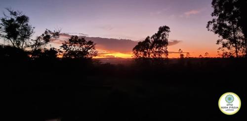 a sunset over a field with trees in the foreground at Sítio Roda d'Água in Lagoa Santa