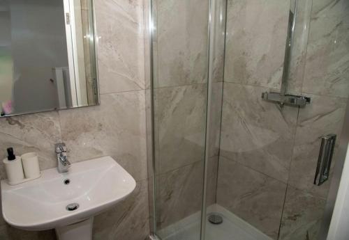 een badkamer met een wastafel en een douche met een glazen deur bij Luxury two bedroom apartment in Wilpshire