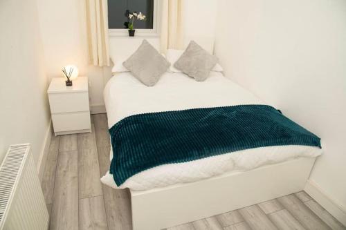 Luxury two bedroom apartment في Wilpshire: غرفة نوم بسرير وبطانية خضراء وبيضاء