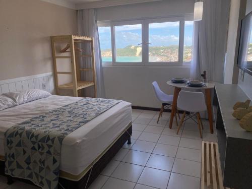 1 dormitorio con cama, mesa y ventana en Flat com vista para o mar - Ponta Negra, en Natal