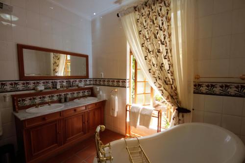 a bathroom with a tub and two sinks and a window at Kleine Constantia Boutique Guest House in Roodepoort