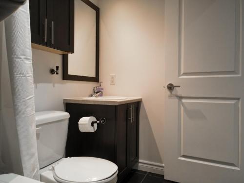 a bathroom with a toilet and a sink and a door at Modern Loft Chute-Montmorency in Boischâtel