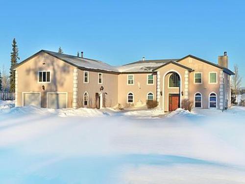 une grande maison avec de la neige devant elle dans l'établissement Lake Vista Grand Villa - 7BR, Hot Tub, Sauna, Wi-Fi, à Kenai