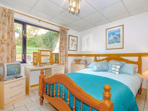 a bedroom with a large bed and a television at Brunels Cottage in Neyland