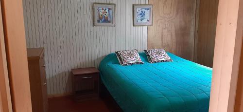 a bedroom with a blue bed with two pillows on it at Refugio de Tranquilidad: Cabaña de 2 Dormitorios con WiFi y Estacionamiento Privado en Río Bueno in Río Bueno