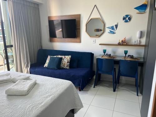 a bedroom with a bed and a blue couch and a table at Flat Mana Beach Pono 216 na Praia de Muro alto in Ipojuca