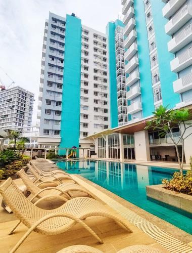 a swimming pool with lounge chairs in front of tall buildings at Minimalist Condo Studio at Messavire Garden Residence near Ruins Bacolod in Bacolod