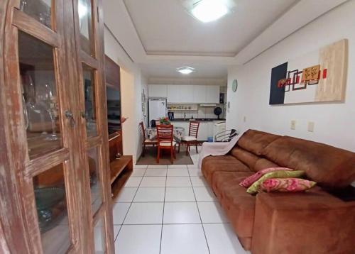 ein Wohnzimmer mit einem braunen Sofa und einer Küche in der Unterkunft Aconchegante apto, quadra do mar, no Tabuleiro! in Barra Velha