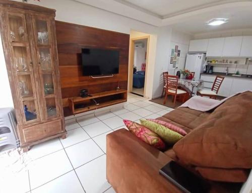 a living room with a brown couch and a tv at Aconchegante apto, quadra do mar, no Tabuleiro! in Barra Velha