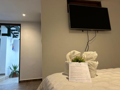 a flat screen tv on a wall above a bed at Casa Hotel El Encanto de Villa in Villa de Leyva
