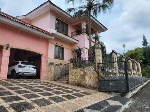 różowy dom z samochodem zaparkowanym na podjeździe w obiekcie Villa Bukit Cipendawa Cipanas w mieście Cipanas