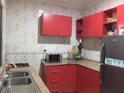 uma cozinha com armários vermelhos e um frigorífico de aço inoxidável em 1 bedroom apartment em Ibadan