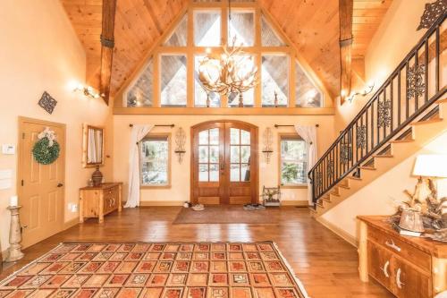 an open living room with a staircase and a vaulted ceiling at Colibri Cabin on a peaceful lake, with a hot tub! in East Bernstadt