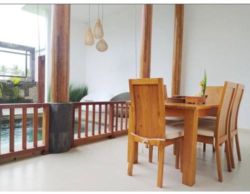 - une table à manger en bois et des chaises sur une terrasse couverte dans l'établissement VilaDewaScaAcomodation, à Ubud