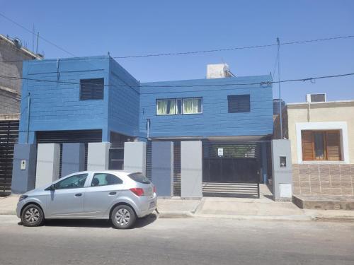 a silver car parked in front of a blue building at Dptos Salim in San Fernando del Valle de Catamarca
